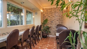 A restaurant with a long table, chairs, and potted plants. - Vendange Carmel Inn & Suites (Carmel)