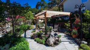 A garden with a pergola, stone pathway, and outdoor seating area. - Vendange Carmel Inn & Suites (Carmel)