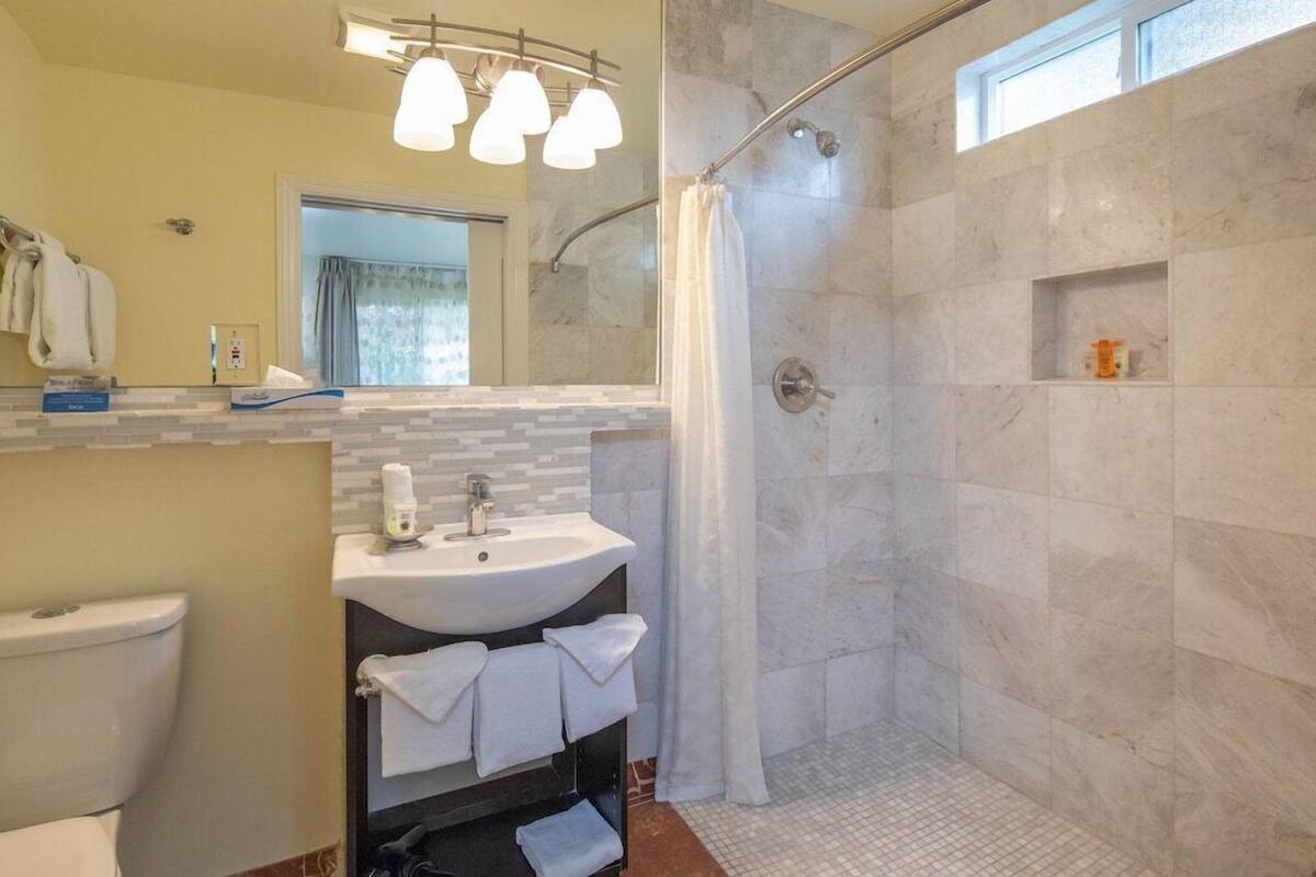 A bathroom with a shower, sink, and toilet.