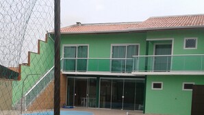 A two-story building with a green exterior, a swimming pool, and a gravel driveway. - House in Balneário Barra do Sul - SC  (Balneário Barra do Sul)