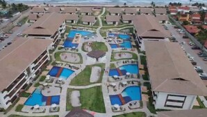 Eine Vogelperspektive zeigt ein Resort mit mehreren Schwimmbecken, einem Innenhof und direktem Zugang zum Strand.