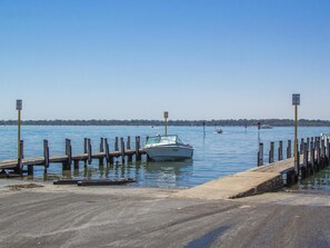 A boat docked at a pier with a clear view of the water and distant shoreline. - Twin Waters Caravan Park - Dawesville (Dawesville)
