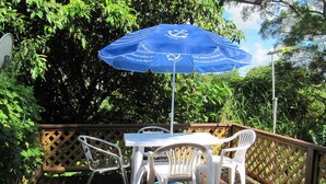 A wooden deck with a table and chairs, an umbrella, and a lattice railing.