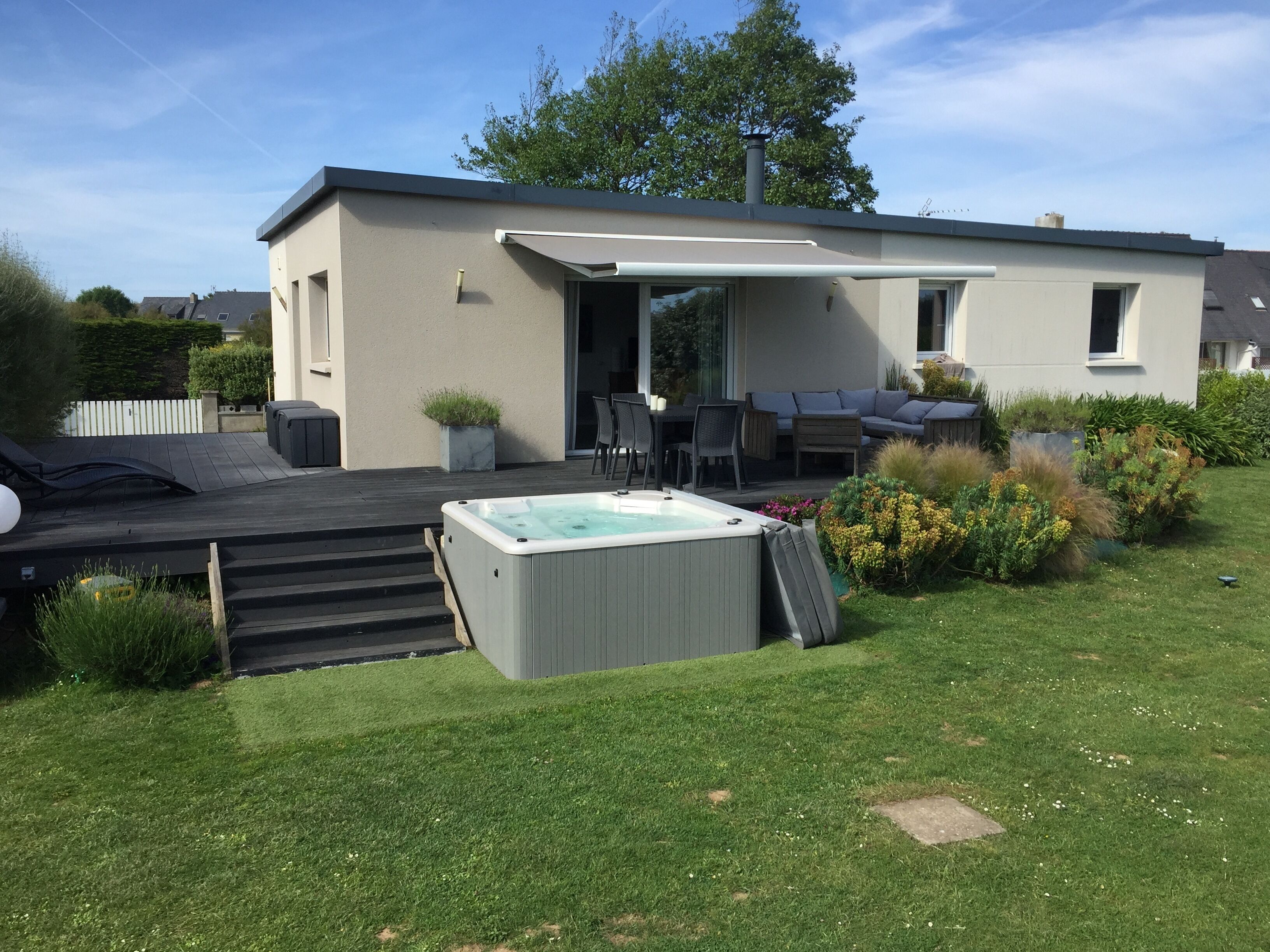 A modern house with a patio, a hot tub, and outdoor furniture.