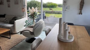 A modern living room with a sofa, a dining table, and a view of a garden. - A haven of peace with Spa at 2 steps from the beach (Cléder)