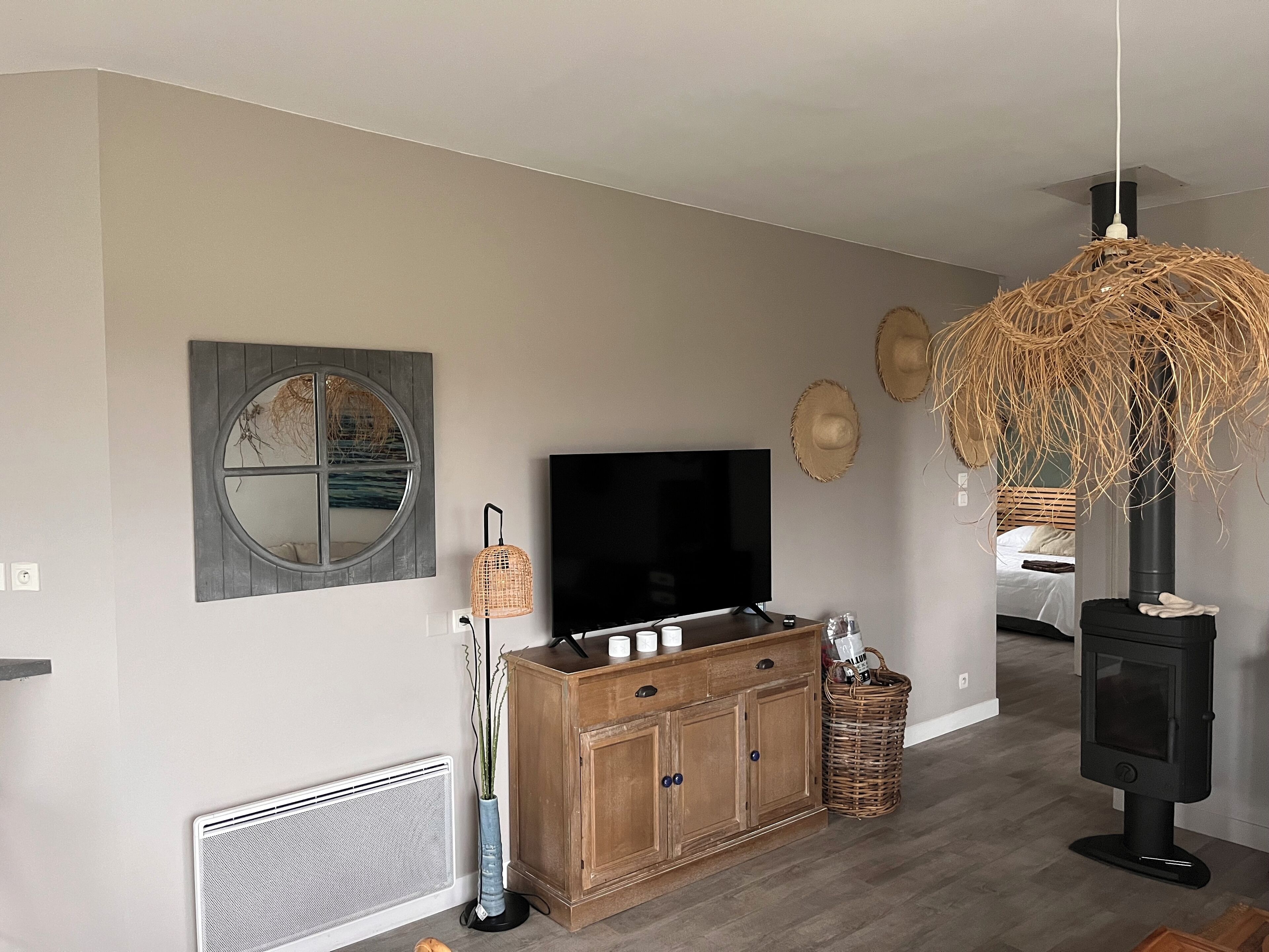 A living room with a TV, wooden cabinet, wicker lamp, and a fireplace.