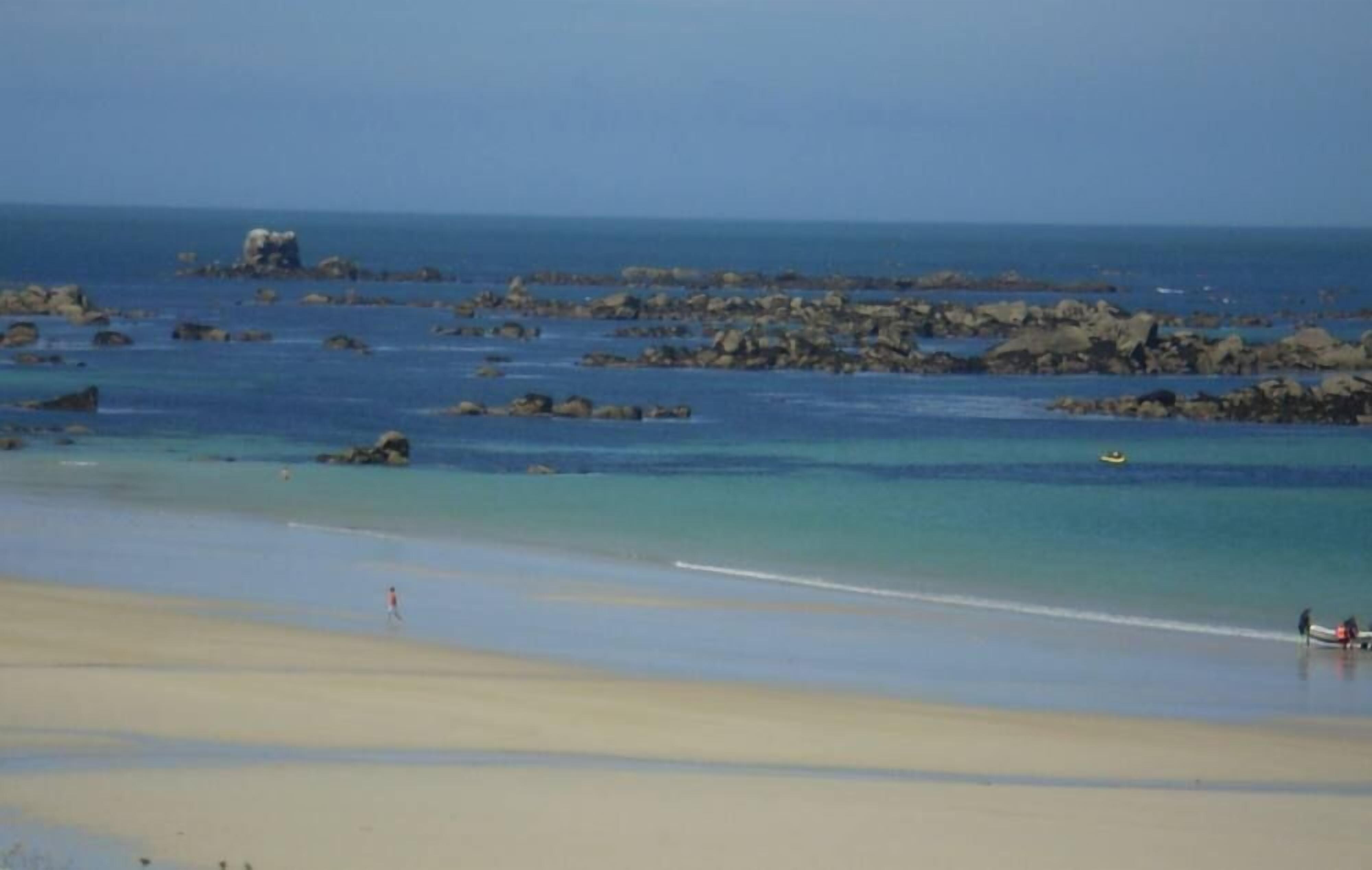 A beach with clear water, rocks, and a distant island.