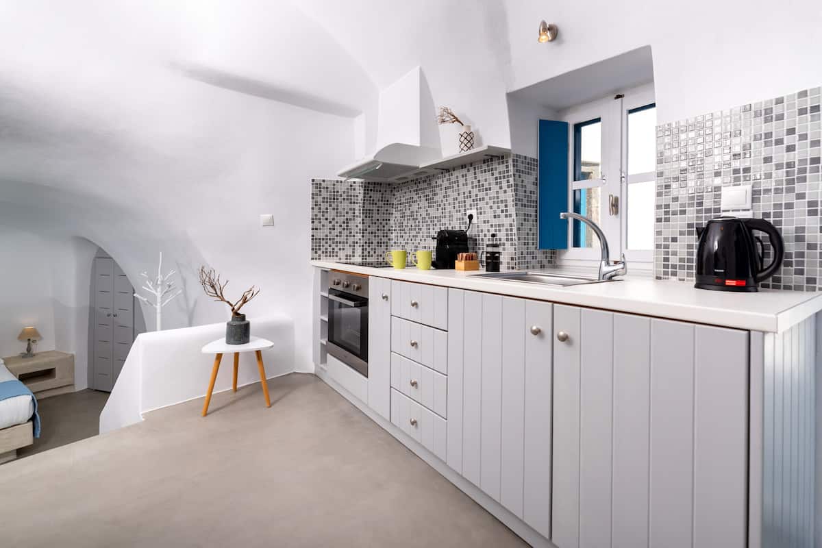 A modern kitchen with white cabinets, a tiled backsplash, and a coffee machine.