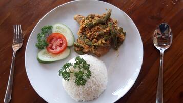 A plate with white rice, a tomato slice, cucumber slice, green beans, and a garnish of parsley.