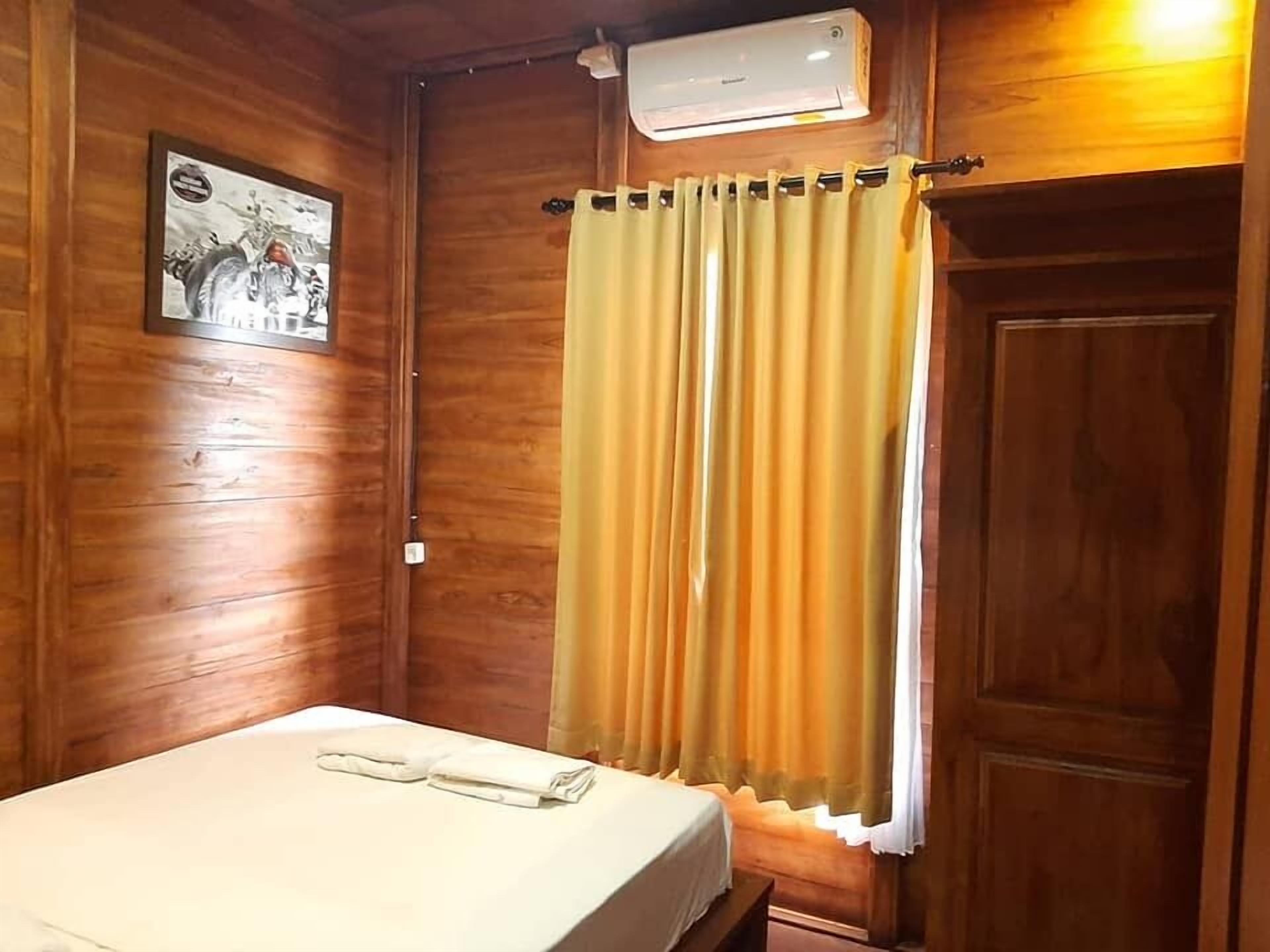 A wooden room with a bed, a curtain, and an air conditioning unit.