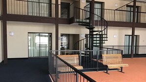Ein großzügiger Innenbereich mit einer zentralen Wendeltreppe, mehreren Balkonen und Holzbanken.