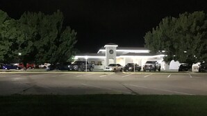 Ein Parkplatz mit mehreren Autos und einem Gebäude mit einem Glockenturm.
