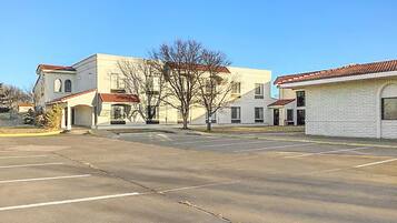 A parking lot with a building featuring a red-tiled roof and a white facade.
