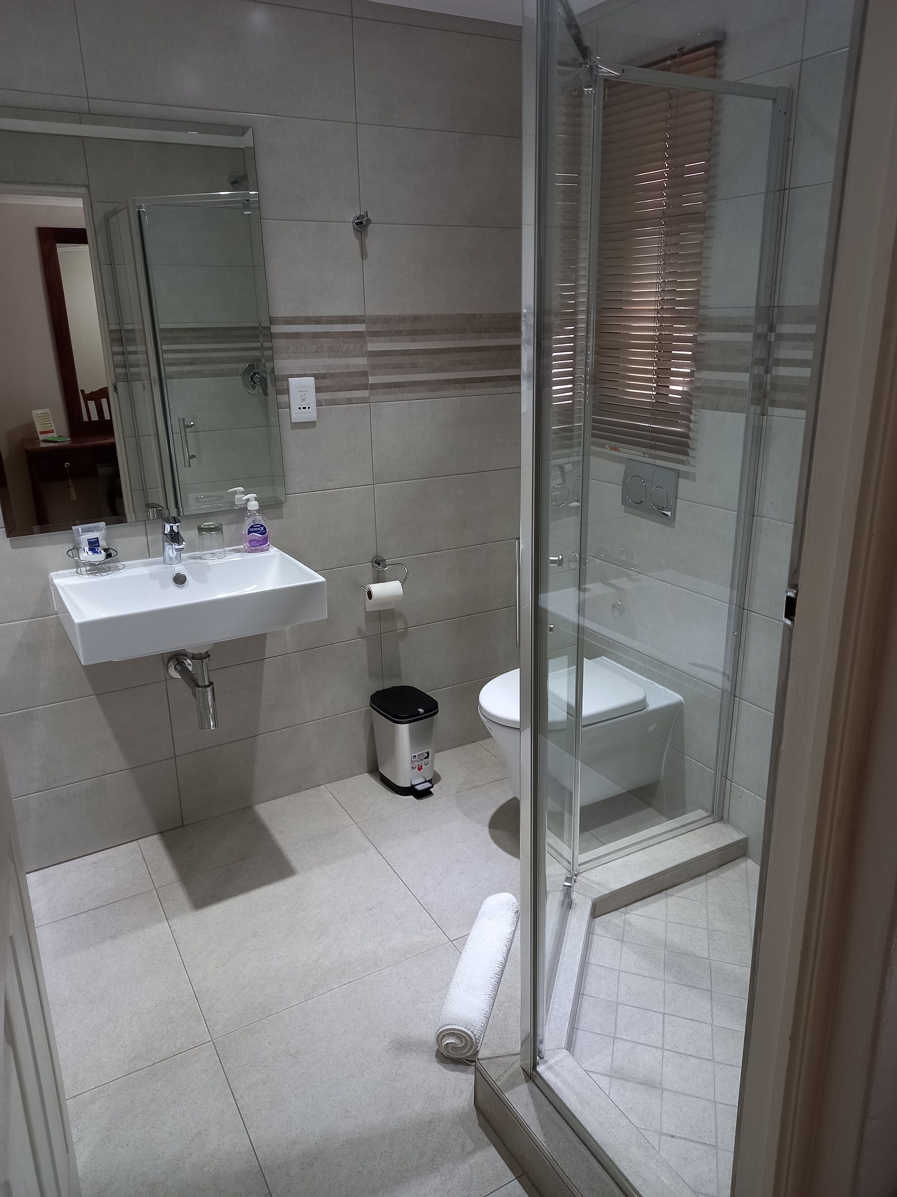 Un baño moderno con ducha acristalada, un lavamanos blanco y un inodoro.