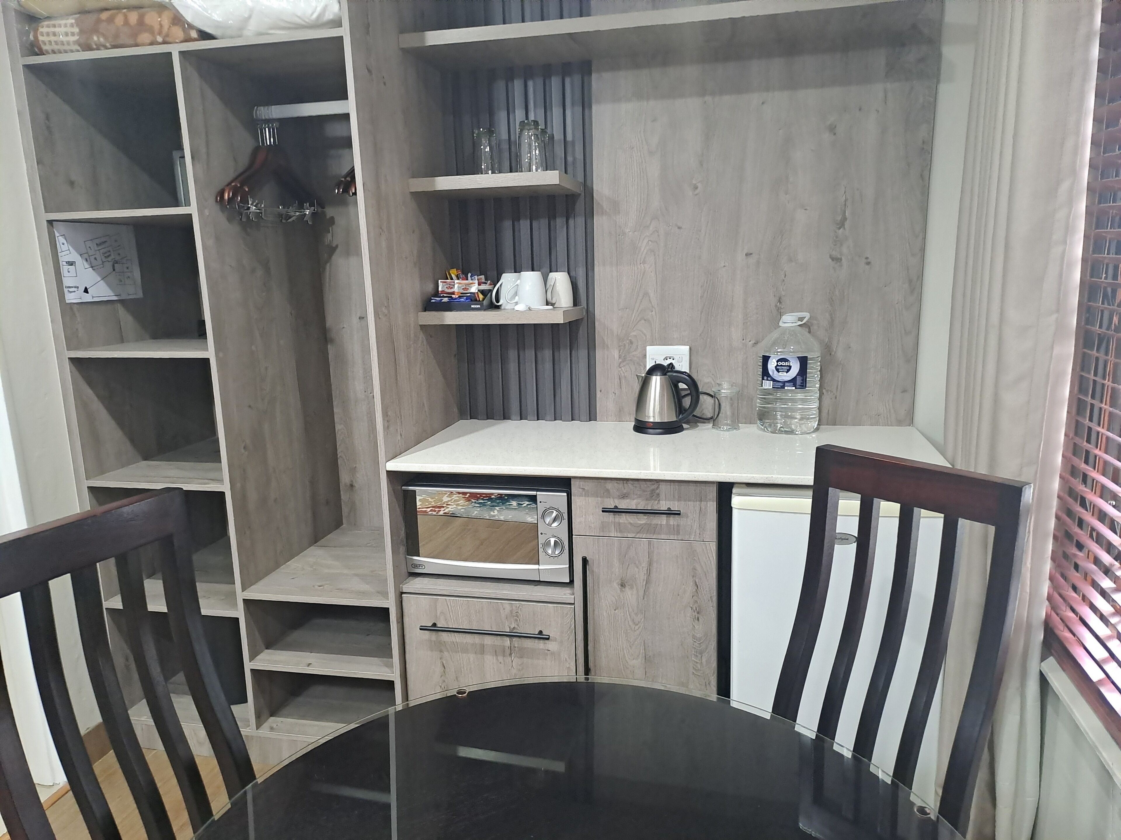 A compact kitchen with a dining table, chairs, and a refrigerator.