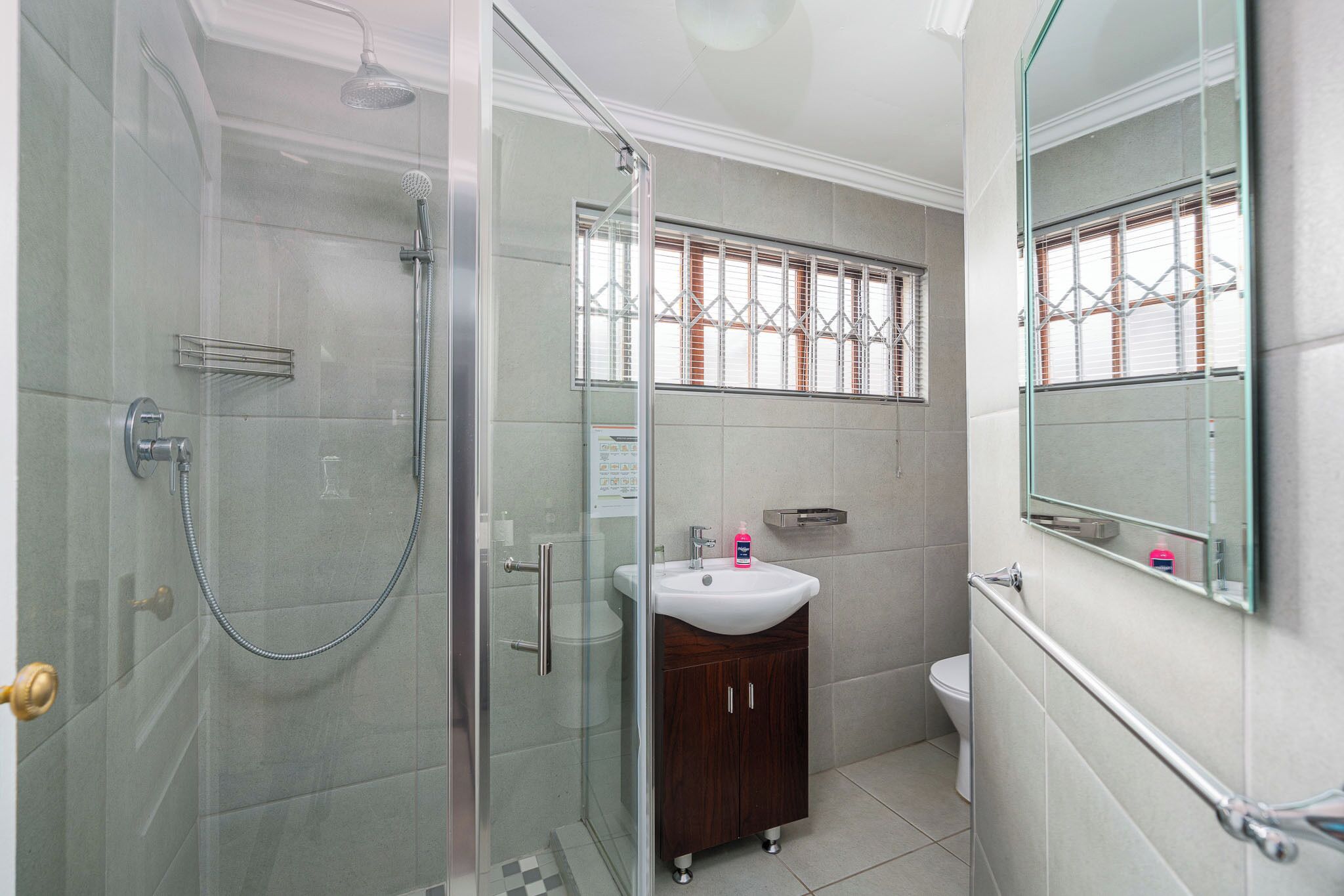 Un baño con ducha de vidrio, lavamanos blanco y un inodoro.