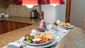 A breakfast buffet with various food items and a bottle of wine on a granite countertop. - Kuiersaam Gastehuis (Secunda)