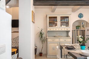 A kitchen with a central island, a dining table with chairs, and a cabinet with glass doors.