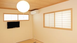 A room with tatami flooring, a ceiling fan, a mounted air conditioner, a flat-screen TV, and shoji screens. - JL Guest House Daikokucho (Osaka)