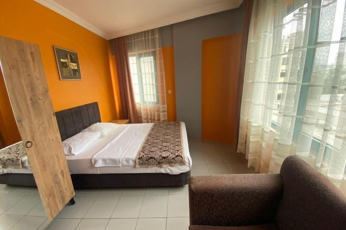 A bedroom with a bed, a chair, and a window with curtains.