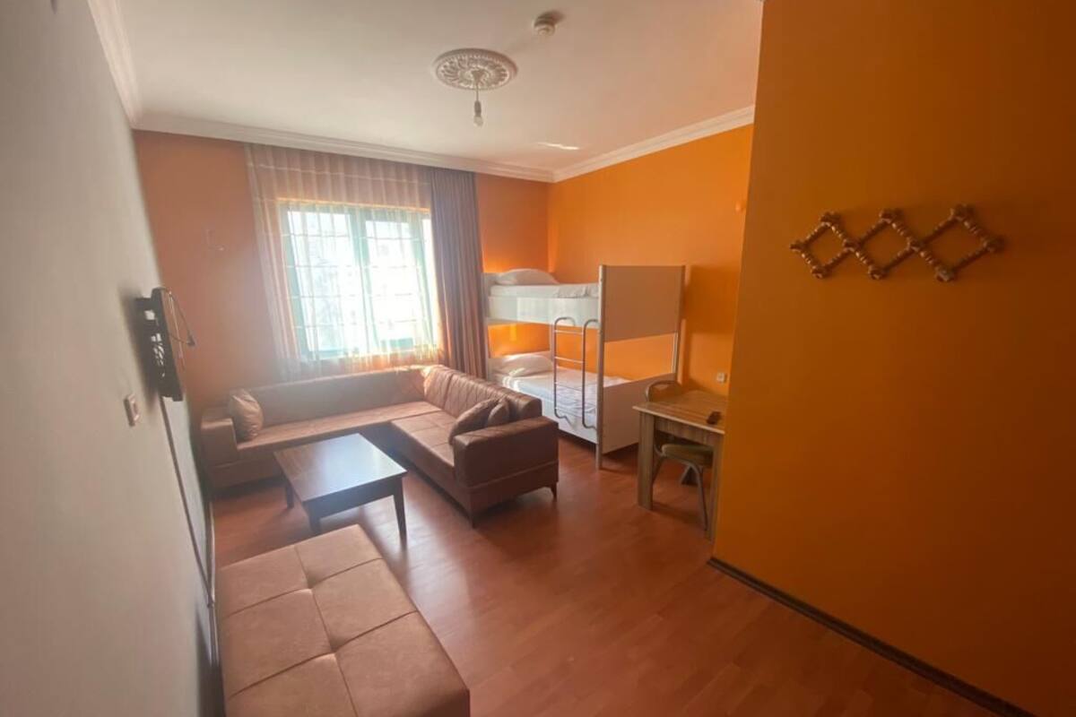 A room with a sofa, a small table, a bunk bed, and a window with curtains.