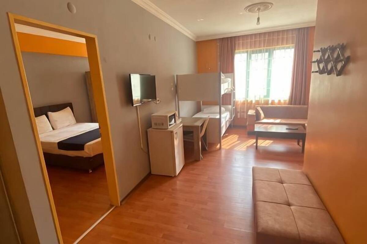 A hotel room with a bed, desk, chair, TV, and a sofa.