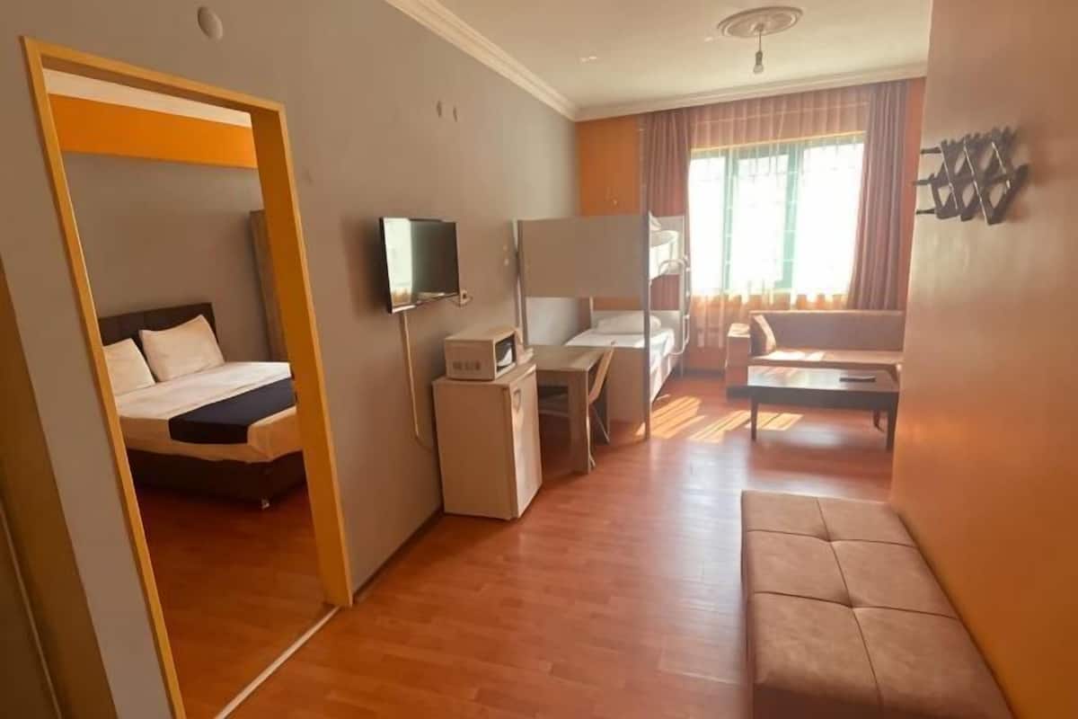 A hotel room with a bed, desk, chair, TV, and a sofa.