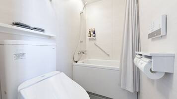 A modern bathroom with a white toilet, a bathtub, and a shower. There are toiletries on a shelf and a towel rack.