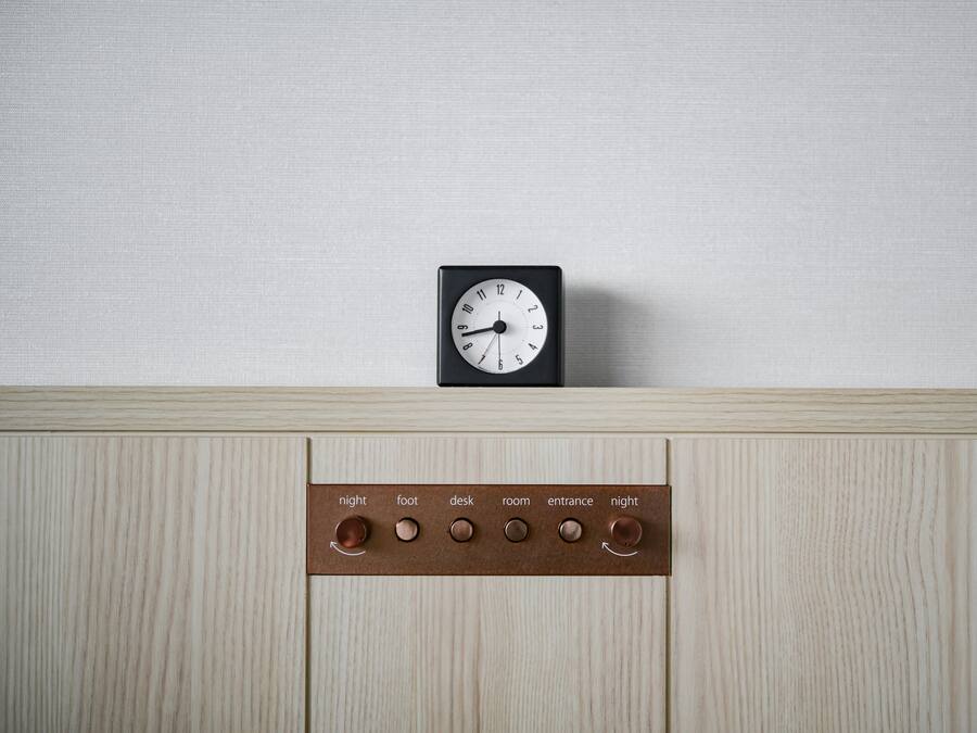 A wall-mounted clock and a control panel with buttons labeled "night," "foot," "desk," "room," "entrance," and "night."