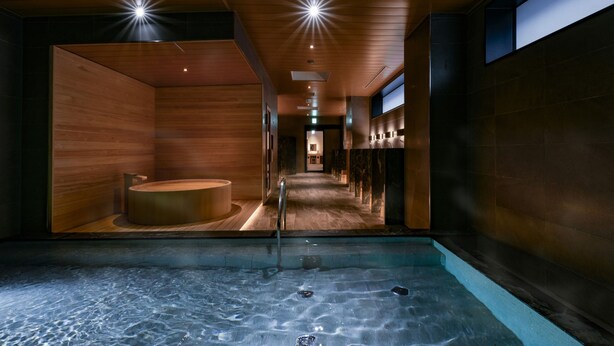 Een moderne spa met een centrale jacuzzi, houten wanden en een betegelde vloer.