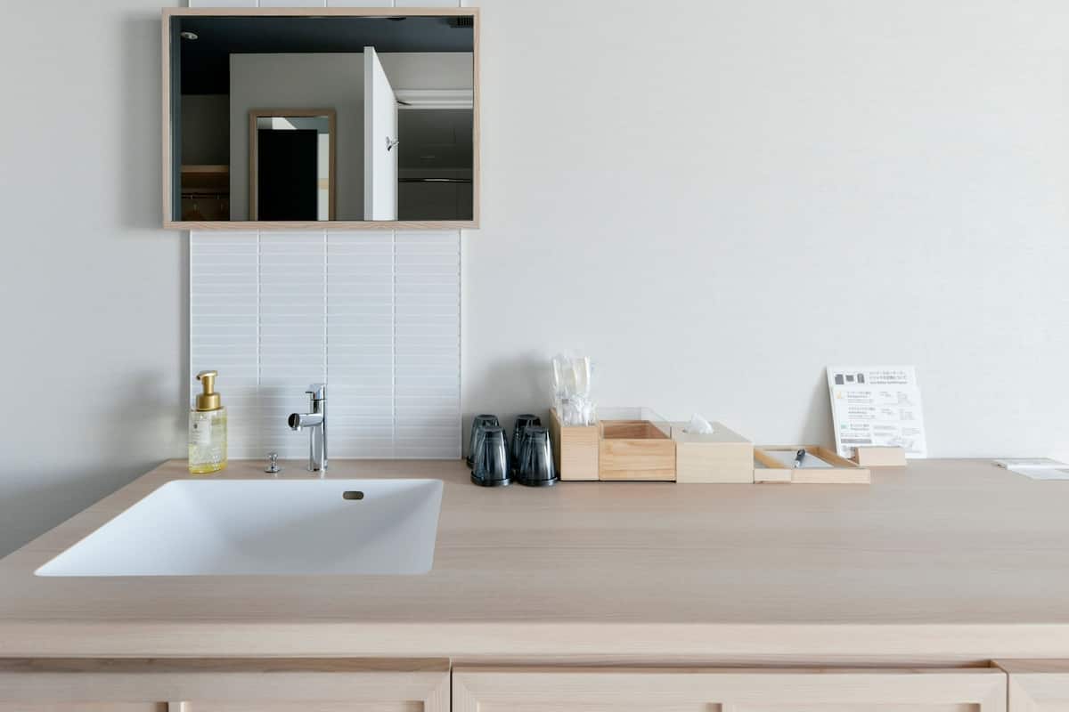 A bathroom with a large sink, a mirror, and a wooden vanity with drawers.