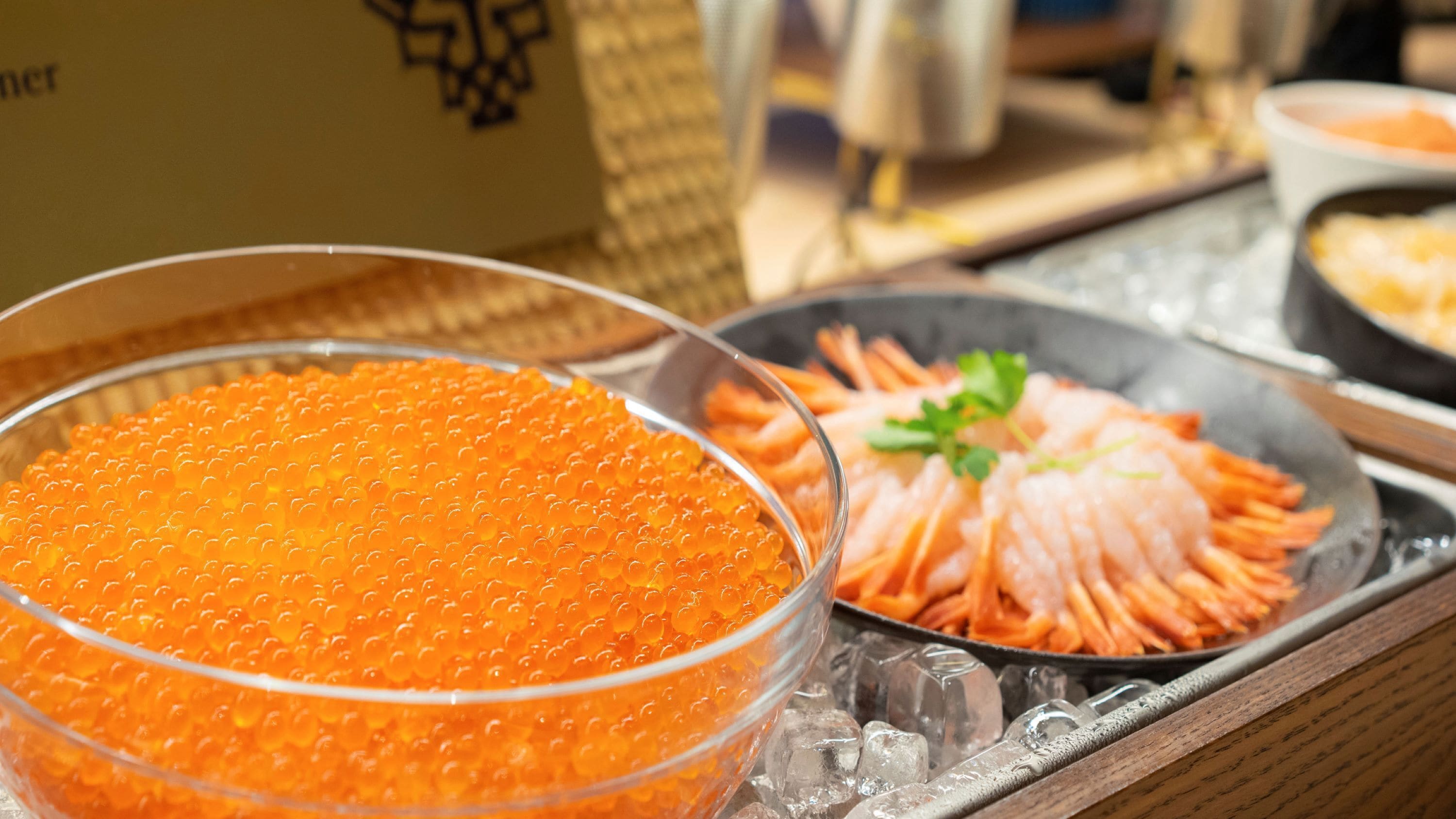 A buffet table with a bowl of orange caviar and a plate of sliced fish garnished with parsley.