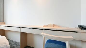 A modern hotel room with a minimalist desk, a chair, and a phone.