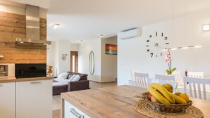 Een moderne keuken met een houten aanrecht, een eethoek met een houten tafel, en een wandklok.