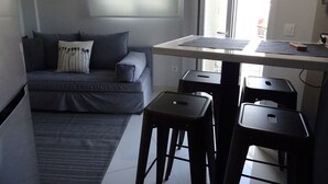 A modern living room with a grey sofa, a small table, and two black stools. - Minimal Luxury near Acropolis (Athens)