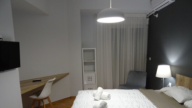 A hotel room with a bed, a desk, a chair, a TV, and a lamp. - Minimal Luxury near Acropolis (Athens)