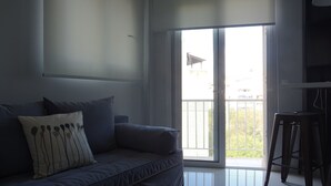 A modern living room with a grey sofa, a small table, and a sliding glass door leading to a balcony. - Minimal Luxury near Acropolis (Athens)