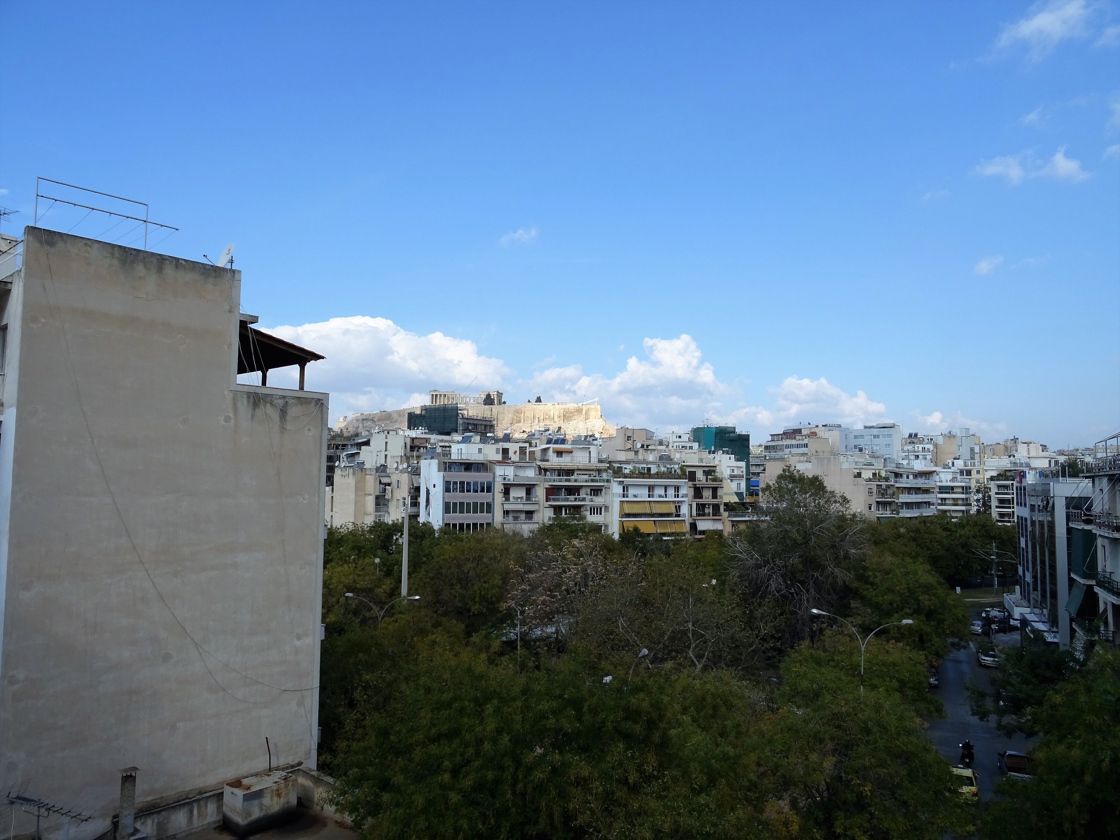 A cityscape with modern buildings, a prominent ancient structure in the background, and a mix of residential and commercial areas.