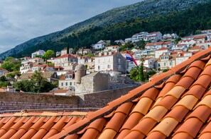 A coastal town with terracotta-roofed buildings, a prominent flag, and a stone wall. - Apartments Zoro (Dubrovnik)