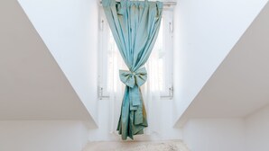 Une pièce avec une fenêtre, un rideau noué en forme de nœud et un socle en pierre.