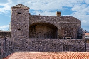 Uma fortaleza de pedra com uma grande entrada em arco e uma torre pequena.