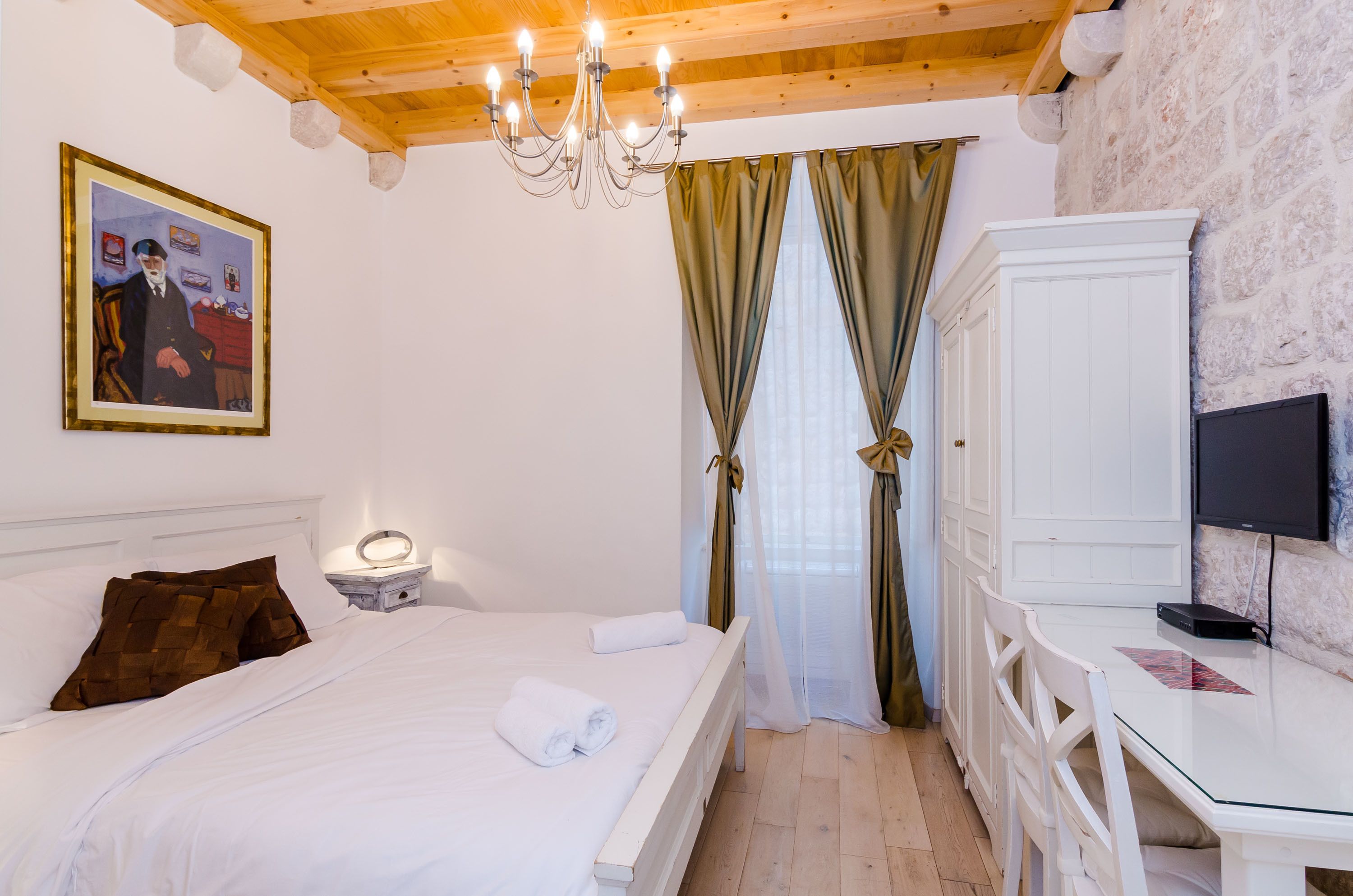 Un dormitorio con cama, mesita de noche con lámpara, televisor en un mueble bajo y armario.