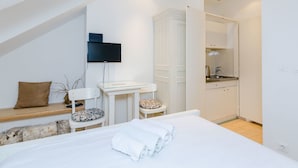 Une chambre moderne avec un grand lit, un bureau, une chaise et un téléviseur fixé au mur.