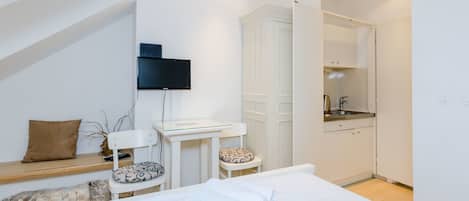 Une chambre moderne avec un grand lit, un bureau, une chaise et un téléviseur fixé au mur.