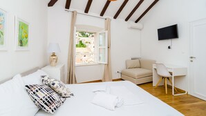 Un dormitorio con una cama, un escritorio, una silla, un televisor y una ventana con cortinas.