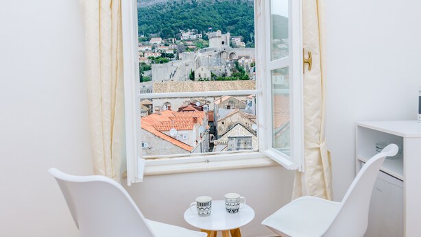 Una habitación con vistas a un pueblo histórico, una pequeña mesa con dos sillas y un armario blanco.
