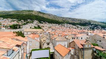 A historic town with stone buildings and red-tiled roofs, featuring a prominent church and a hill in the background.