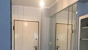 Quarto com duas portas brancas, divisória de vidro e chão ladrilhado.