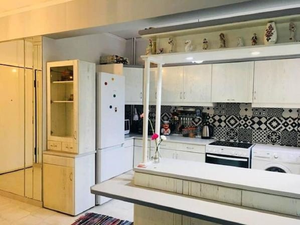 Enjoy cooking in this well-equipped kitchen with a central island, featuring a refrigerator, stove, and sink.