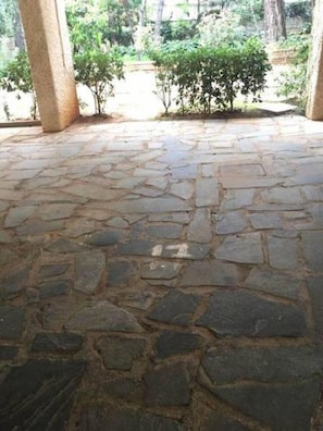 Surrounded by lush greenery, this tranquil courtyard features a unique stone-paved design and elegant columns.
